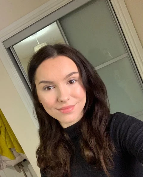 a young woman with long dark hair and dark top smiling at the camera